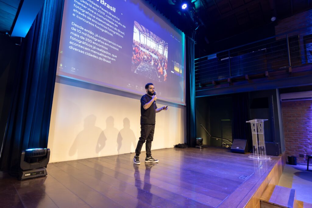 Spreker op een verlicht podium met een grote presentatie